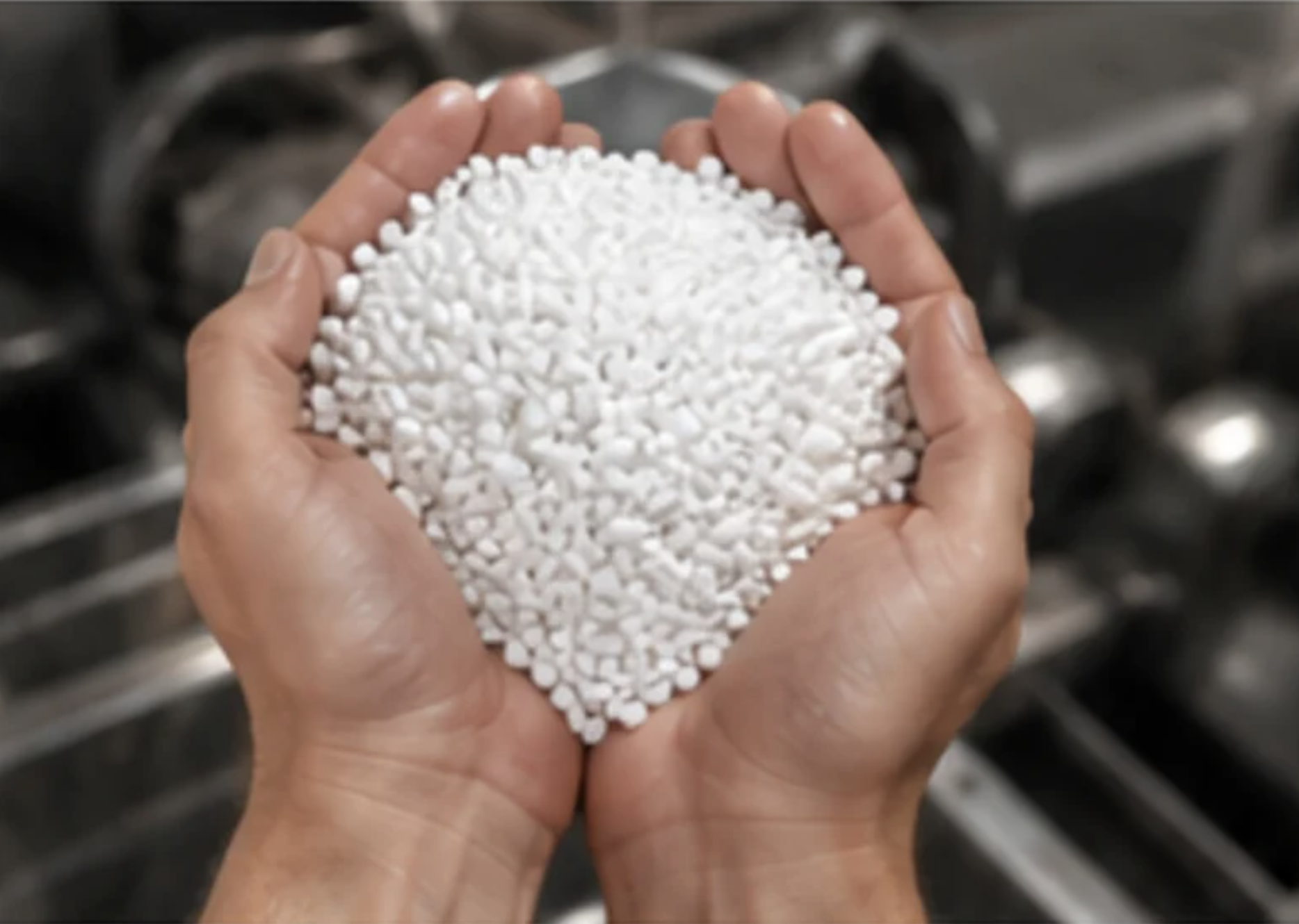 Hands holding white masterbatch granules